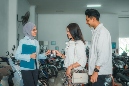 veiled woman waitress handing over a new motorcycle ownership sign to a couple customers at the...