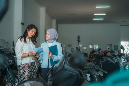 young woman chatting with a veiled saleswoman at a motorcycle showroomの写真素材
