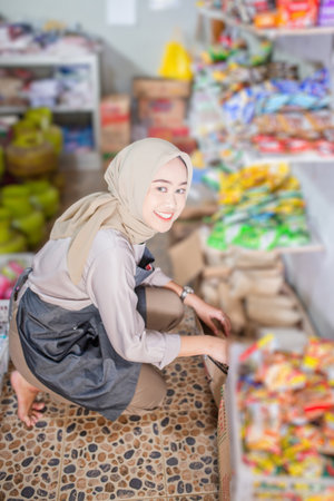 A cheerful woman is arranging items in a grocery store for an appealing shopping experienceの写真素材
