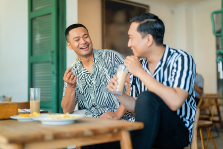 Two close friends share a joyful moment enjoying food and drinks in a cozy cafeの写真素材