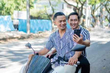 Two friends joyfully ride a scooter outdoors, enjoying sunshine, laughter, and memoriesの写真素材