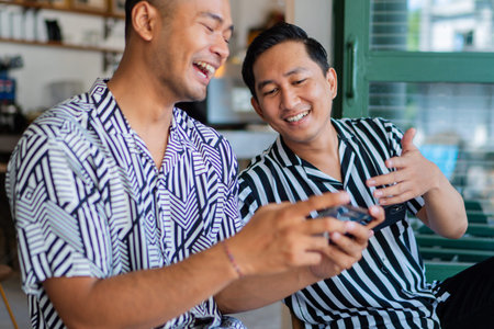 Two friends sharing a joyful moment as they smile and game together in a stylish cafe