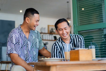 Two close friends sharing hearty laughter and memorable good times together over coffeeの写真素材