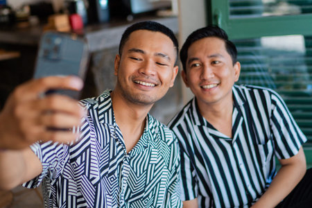 Two friends smiling while capturing a fun outdoor moment with a selfie togetherの写真素材