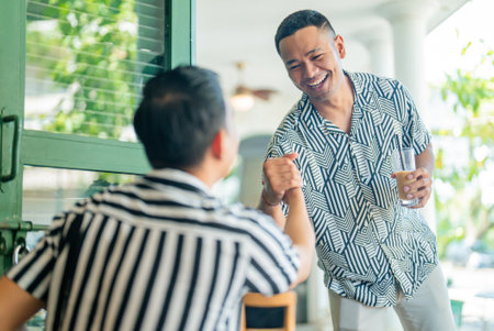 Two friends enjoying a warm greeting at a caf with beveragesの写真素材