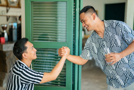 Two enthusiastic men engage in an exciting and fun arm wrestling challenge indoorsの写真素材