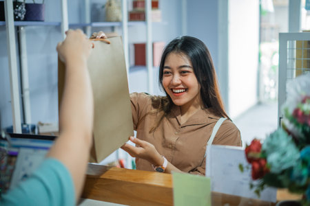 beautiful Asian girl receives a paper bag while buying a gift at a gift shop counterの写真素材