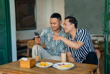 Two friends share laughs and snacks in a cozy caf settingの写真素材