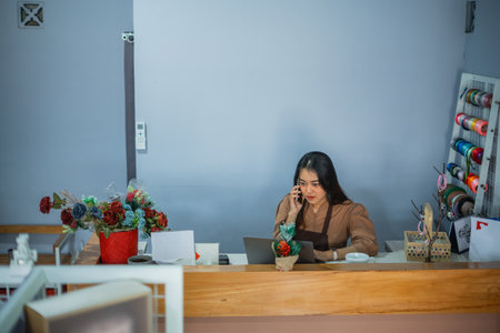 attractive enterprising girl on the phone behind her shop counterの写真素材