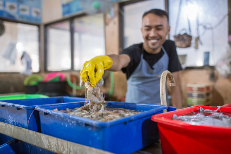 A cheerful fisherman skillfully handles fresh seafood at a vibrant local market full of lifeの写真素材
