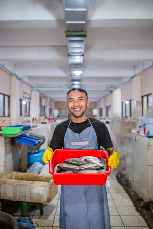 A cheerful fishmonger showcases a basket of fresh seafood in a busy market, attracting customersの写真素材
