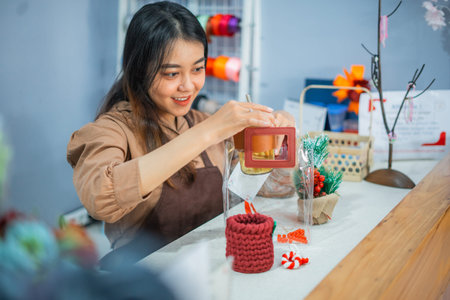 Asian girl shop assistant wraps items in transparent plastic at a gift shop