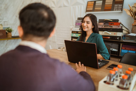 beautiful shopkeeper welcoming the male customer at her desk inside the shop