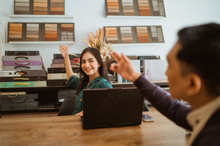 asian male customer pointing on the material sample catalogue at the wall that showed by the female shopkeeperの写真素材