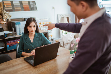 frustrated female shopkeeper glared to the male shop owner that scolding and pointing at her inside the interior shopの写真素材