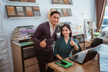 couple of asian interior shop crew looking at the camera with thumbs up while working at interior...