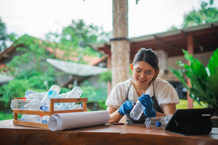 asian woman making handmade craft from plastic bottle with tutorial from internetの写真素材