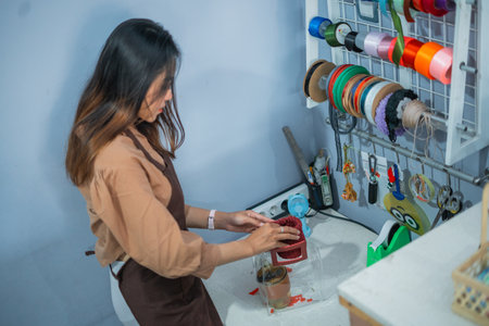 woman shopkeeper wrapping goods in a gift box at a gift shopの写真素材