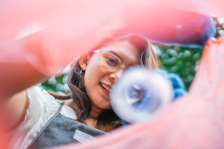 low angle view of asian woman throwing plastic bottle into plastic bag, recycle concept