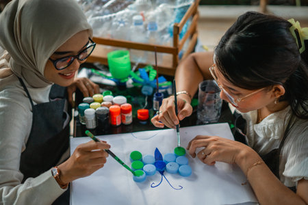 women holding brush and painting on plastic bottle cap with happy faceの写真素材