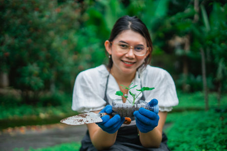 asian woman holding recycled plastic bottle for planting seedling in the gardenの写真素材