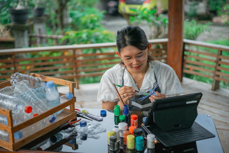 high angle view of asian woman painting recycled plastic bottle craftの写真素材