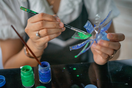 crop view of female hand painting recycled plastic bottle craftの写真素材