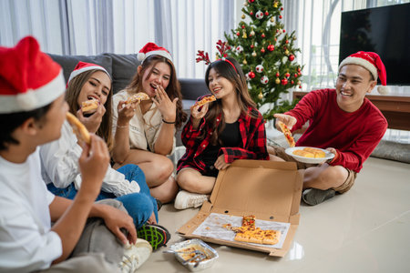 joyful people spending christmas holiday with friends, eating pizza for dinnerの写真素材