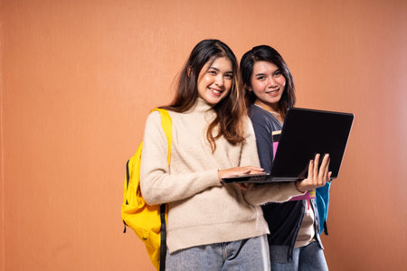 Two young women are joyfully collaborating on a laptop, enjoying their work togetherの写真素材