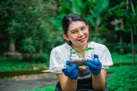 asian woman planting seedling using recycle plastic bottle waste, recycle and reuse conceptの写真素材
