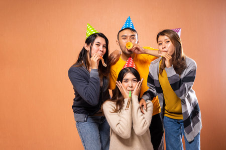 A group of friends joyfully celebrates, wearing colorful party hats and making funny faces