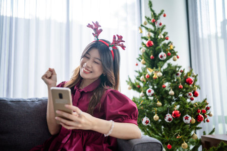 asian woman feeling excited at christmas day, holding phoneの写真素材