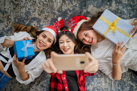 young women using phone to taking selfie picture at christmas, when laying down, high angle view