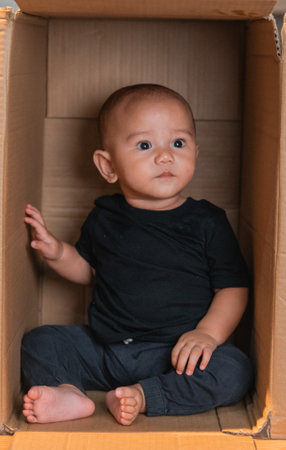 A curious toddler joyfully explores a cardboard box, demonstrating innocence and curiosityの写真素材