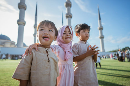 Three joyful kids in colorful traditional attire celebrate their culture near a mosque