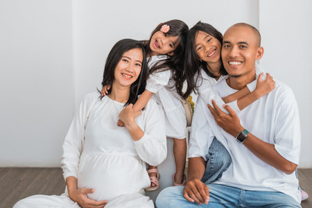 A pregnant woman is comfortably sitting on the floor with her loving family, sharing joyful moments together and enjoying each others companyの写真素材