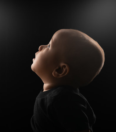 A thoughtful and inquisitive child gazes upward at the warm light with wonder and curiosityの写真素材