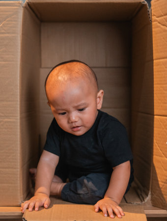 A curious and playful baby is completely fascinated and enchanted by a cardboard boxの写真素材