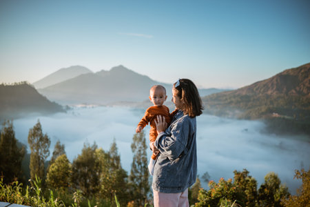 A serene moment of a mother and her baby with majestic mountains in the background.の写真素材