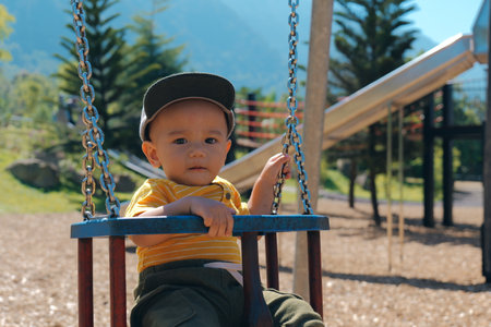 On a delightful sunny day, a joyful toddler swings happily while surrounded by natures beautyの写真素材