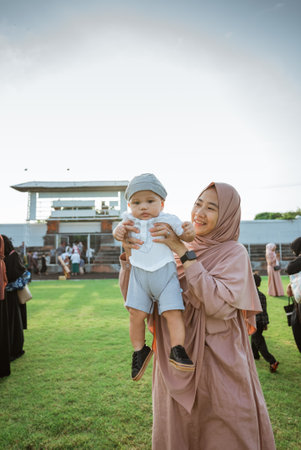 A woman gently cradles a baby in her arms while standing in a beautiful field filled with vibrant grass and wildflowers all around herの写真素材