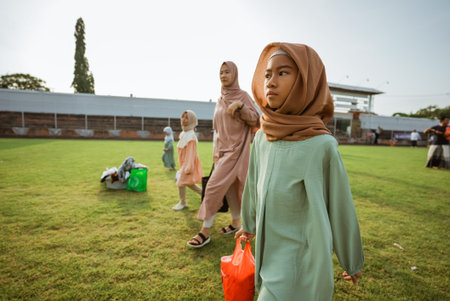 A woman wearing a colorful hijab is walking leisurely in a beautiful field alongside two other women...