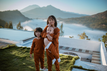 A group of happy kids in matching outfits stand together in a scenic natural landscapeの写真素材