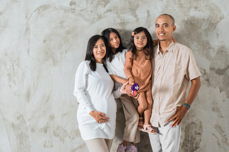 A cheerful family is happily posing together for a memorable picture in front of a colorful wall...