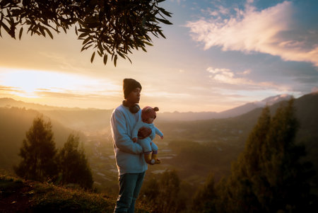 A touching moment of a father holding his child against a stunning sunset backdrop.の写真素材