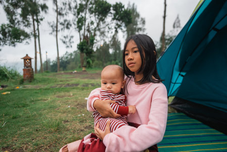 A serene moment captured with a girl gently holding a baby in the wonderful great outdoorsの写真素材
