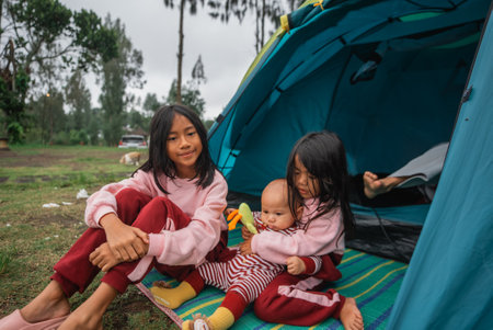 Three joyful children having a fantastic time playing outdoors inside a colorful camping tentの写真素材