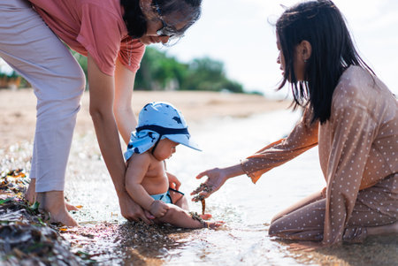 A joyful family moment on a sunny beach, with cheerful toddlers playing happily in the waterの写真素材