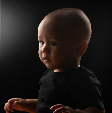A charming baby is beautifully captured in a serene profile framed by soft and gentle lightingの写真素材