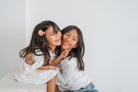 Two little girls are joyfully embracing each other while smiling brightly, showcasing their happiness and friendship in that momentの写真素材
